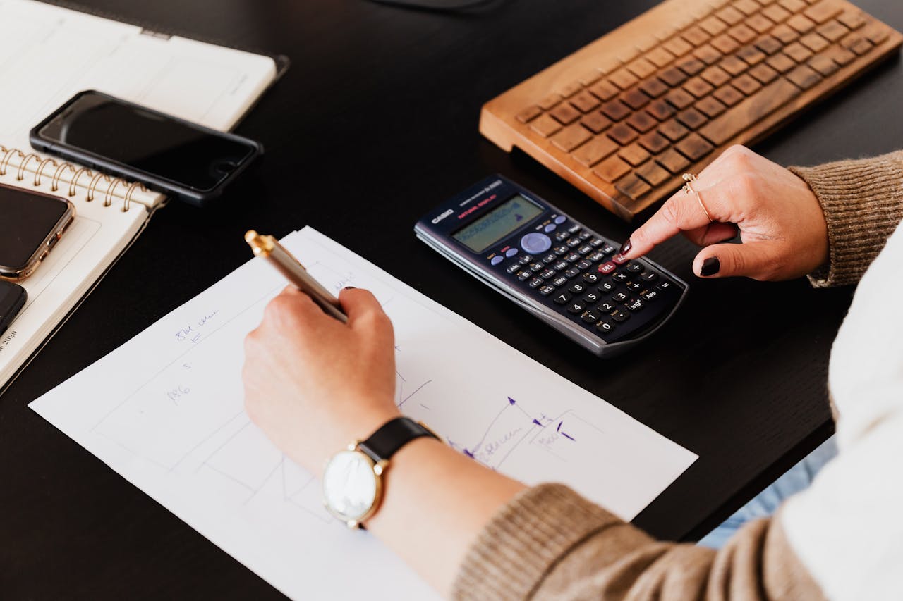 Crafting Captivating Headlines: Your awesome post title goes here Close-up of hands working with a calculator and notebook on a desk, analyzing documents.