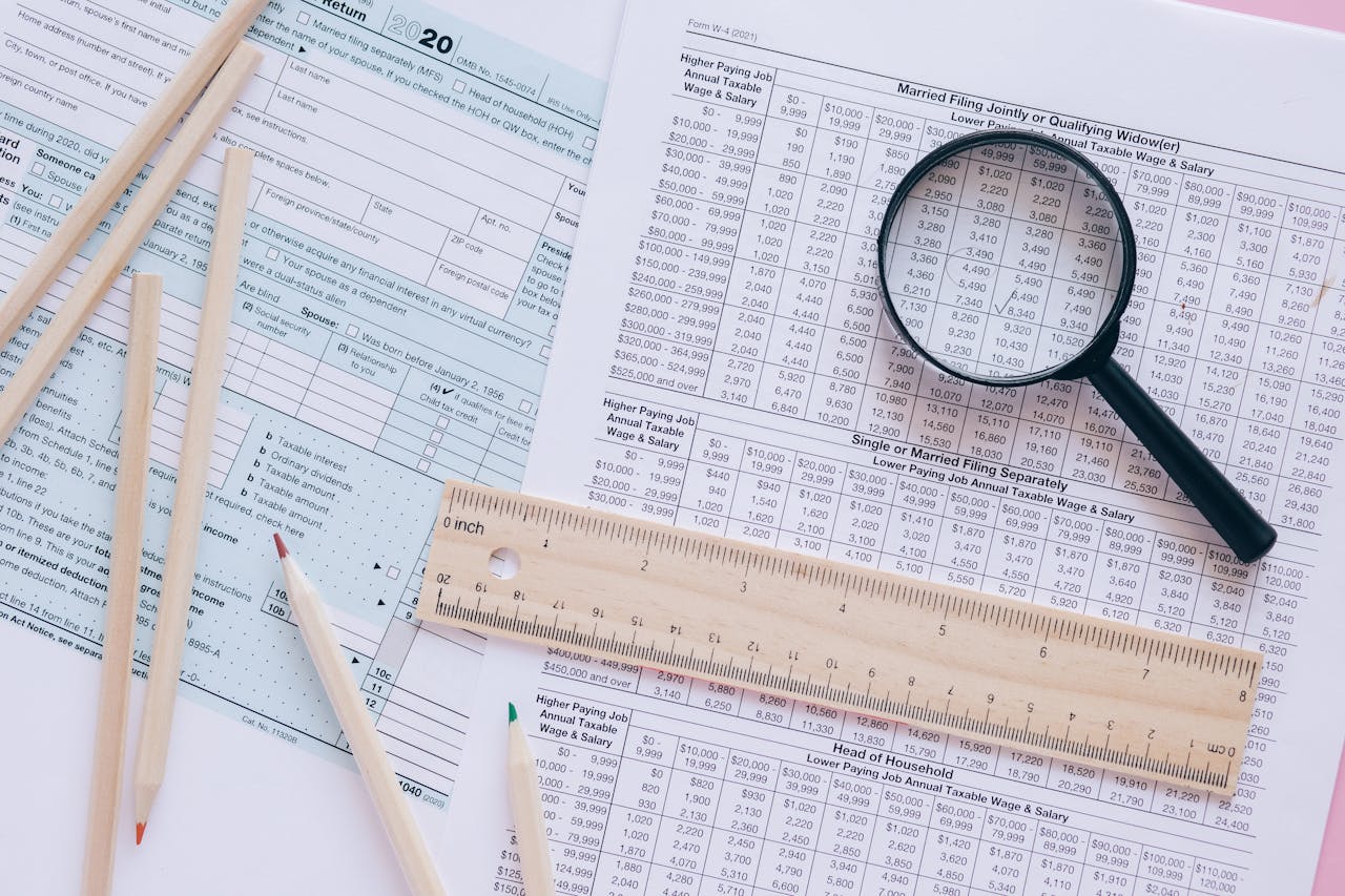 Home A high angle view showing IRS tax forms with pencils, ruler, and magnifying glass for financial planning.